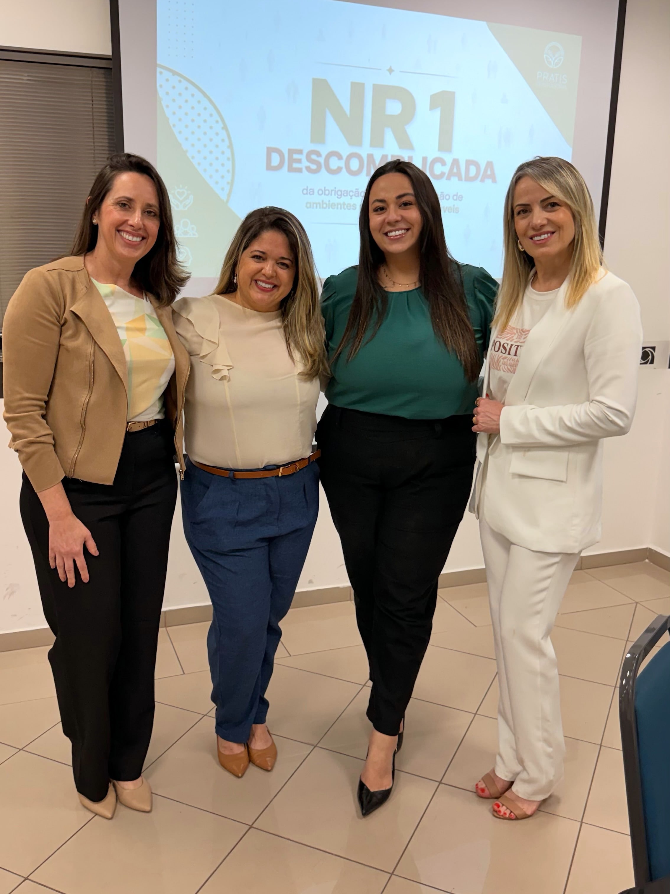 Luanna Lara com as convidadas do workshop NR-1 Descomplicada, em frente ao telão